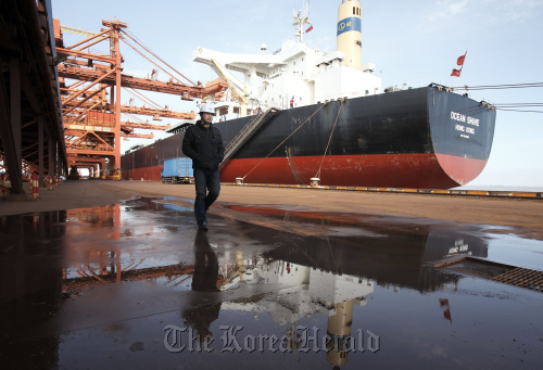 A worker walks near a bulk carrier cargo ship docked at an iron ore transfer and storage center operated by the Shanghai International Port Group in Shanghai.  Bloomberg