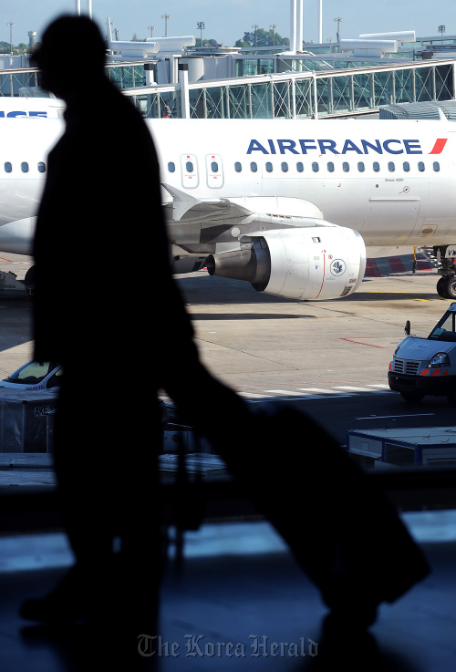 Airline passenger walks through the terminal building past an Air France Airbus A320 aircraft at Roissy Charles de Gaulle airport in Paris. Bloomberg