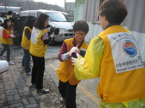 Gyeonggi Suwon International School students help to hand out coals at Guryong Village in Seoul on Saturday.  Gyeonggi Suwon International School