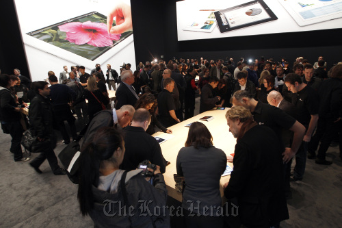 Attendees and members of the media view Apple Inc.’s new version of the iPad tablet computer after its unveiling at an Apple event in San Francisco, California.  Bloomberg