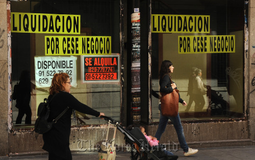 Pedestrians walk past a closed down store in Madrid.  Bloomberg