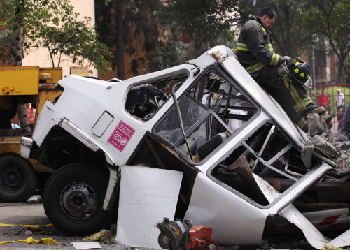 A firefighter rests stands next to part of the structure of a bridge that fell over a public bus during an earthquake, in Mexico City, Tuesday. (AP-Yonhap News)
