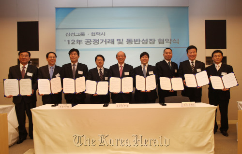 Participants of the fair trade and mutual growth event organized by Samsung and its affiliates hold up their signed treaties at Samsung’s office in southern Seoul on Thursday.  Samsung Electronics