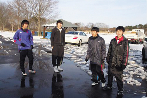 Students at Tohoku Chosen stop their snowball fight to pose for the camera. They were playing next to the destroyed school site, using parked cars as cover. (Yonhap News)