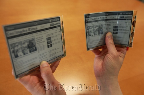 An LG Display official compares the new flexible plastic electronic paper display (right) with the existing glass electronic paper display in Seoul on Thursday.  LG Display