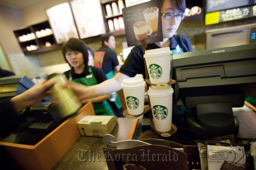Servers help customers at a Starbucks Corp. store in Beijing.  Bloomberg