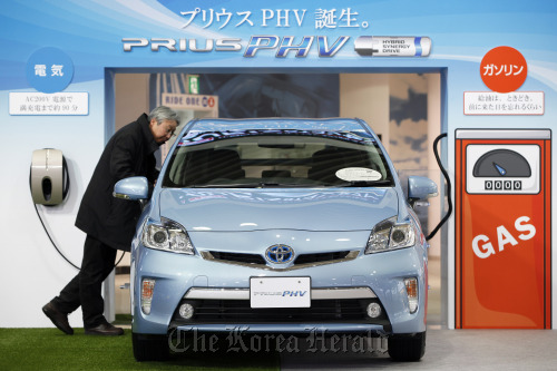 A visitor looks at a Toyota Motor Corp. Prius plug-in hybrid vehicle displayed at the company’s showroom in Tokyo.  Bloomberg
