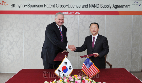 SK Hynix CEO Kwon Oh-chul (right) shakes hands with Spansion CEO John Kispert after signing an agreement on patent cross-licensing and the Korean firm’s NAND supply to the U.S. Flash memory technology provider last week in California.  SK Hynix
SK Hynix CEO Kwon Oh-chul (right) shakes hands with Spansion CEO John Kispert after signing an agreement on patent cross-licensing and the Korean firm’s NAND supply to the U.S. Flash memory technology provider last week.  SK Hynix