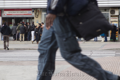 Job-seekers wait outside a job center before opening in Madrid.  Bloomberg