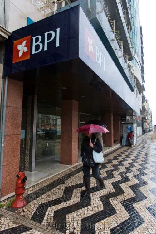 A pedestrian passes the window of a Banco BPI SA branch in Lisbon.  Bloomberg