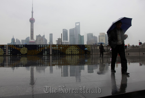 Pedestrians walk near the Huangpu River with the Lujiazui Financial District in the distance in Shanghai.  Bloomberg