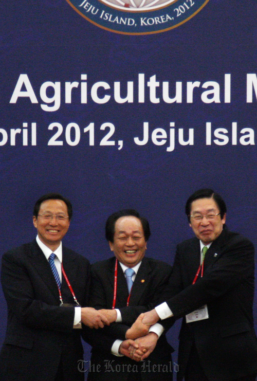 Korean Agriculture Minister Suh Kyu-yong (center) joins hands with his Chinese and Japanese counterparts before starting talks in Jeju on Sunday. At right is Japan’s Farm Minister Michihiko Kano and at left is China’s Agriculture Minister Han Changfu.   Yonhap News