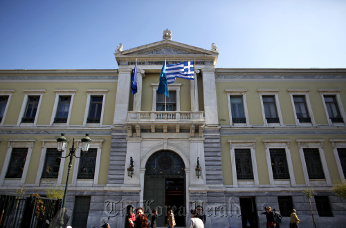 Pedestrians pass the headquarters of the National Bank of Greece SA in Athens.  Bloomberg
