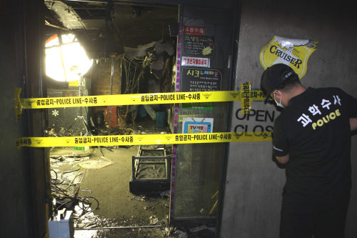 <YONHAP PHOTO-0500> 불탄 부산 노래방 내부 (부산=연합뉴스) 5일 오후 부산 부산진구 부전동의 한 노래방에서 불이 나 9명이 숨지고 25명이 부상당하는 참사가 발생했다. 경찰이 수사를 위해 폴리스 라인을 치고 있다.<<부산경찰청>> 2012.5.6. ljm703@yna.co.kr/2012-05-06 12:26:51/ <저작권자 ⓒ 1980-2012 ㈜연합뉴스. 무단 전재 재배포 금지.>
A police investigator seals the entrance of the fire-ravaged karaoke bar in Busan on Sunday.  Yonhap News