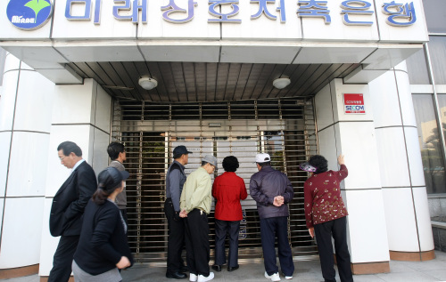 <YONHAP PHOTO-0369> 몰려든 영업정지 저축은행 고객 (제주=연합뉴스) 고성식 기자 = 6일 오전 미래저축은행에 대한 영업정지가 결정된 가운데 주말인데도 고객들이 제주시 이도2동에 위치한 미래저축은행 본점으로 몰려와 경영개선명령 공고문과 고객 안내문을 살펴보고 있다. 2012.5.6 koss@yna.co.kr/2012-05-06 10:07:18/ <저작권자 ⓒ 1980-2012 ㈜연합뉴스. 무단 전재 재배포 금지.>
Clients of Mirae Savings Bank read a notice posted on the door of the bank’s main branch in Jeju on Sunday.  Yonhap News