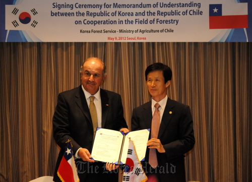 Korea Forestry Service Minister Lee Don-koo (right) and Chilean Agriculture Minister Luis Mayol pose after signing an MOU on cooperation in forestry on Wednesday.                 KFS