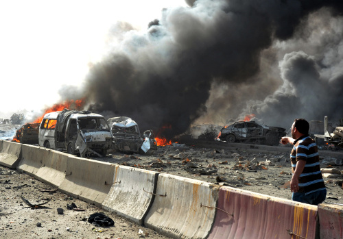 A Syria man (right) reacts as flames and smoke rise from burned cars after two bombs exploded, at Qazaz neighborhood in Damascus on
Thursday. (AP-Yonhap News)