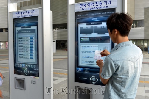 An organizing committee official demonstrates how to use a reservation kiosk machine on the Expo site.    Yeosu organizing committee