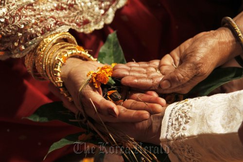 The hand of a Hindi bride is decorated with a flower.  The Daily Star