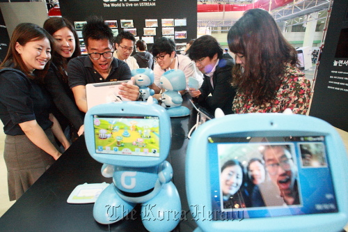 A group of people test the “kibot,” KT’s robot for kids, at the company’s exhibition booth during World IT Show 2012.  KT
