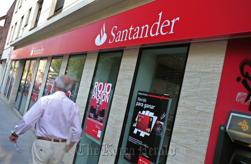 A pedestrian walks past a branch of Banco Santander SA in Madrid.  Bloomberg
