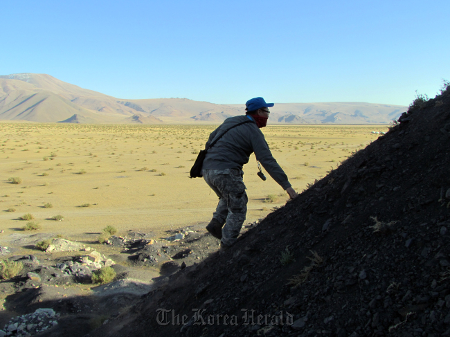 A mine researcher climbs a hill during mine hazards investigation.  KOICA