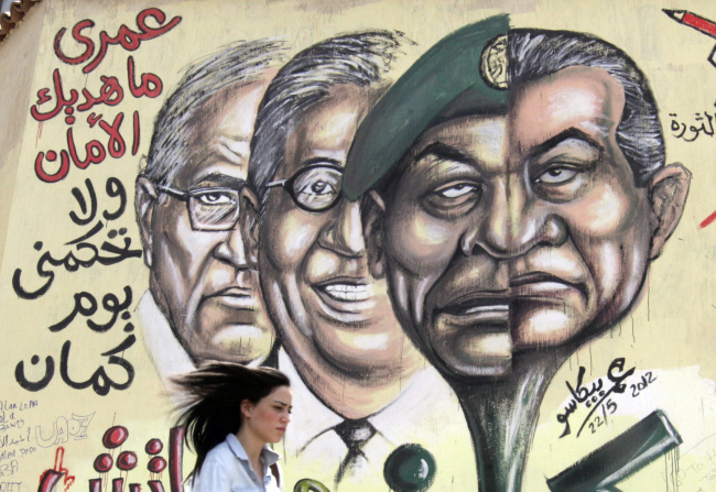 <YONHAP PHOTO-1471> An Egyptian woman walks in front of graffiti with faces of ousted president Hosni Mubarak, right, and military ruler Hussein Tantawi, second right, presidential candidates Amr Moussa, second left, and Ahmed Shafiq, left, with Arabic that reads, "I will never give you peace and you will not rule me another day," at Tahrir Square, the focal point of Egyptian uprising, in Cairo, Egypt, Tuesday, May 29, 2012. A mob set fire late Monday to the campaign headquarters of one of the two Egyptian presidential politicians facing each other in a runoff that will decide a new leader after last year's popular uprising, the first sign of unrest after the voting yielded divisive candidates. (AP Photo/Amr Nabil)/2012-05-29 22:57:30/ <저작권자 ⓒ 1980-2012 ㈜연합뉴스. 무단 전재 재배포 금지.>
An Egyptian woman walks in front of graffiti with faces of ousted president Hosni Mubarak (right), military ruler Hussein Tantawi (second from right), presidential candidates Amr Moussa (second from left) and Ahmed Shafiq (left) with Arabic that reads, “I will never give you peace and you will not rule me another day,” at Tahrir Square, the focal point of the Egyptian uprising, in Cairo on Tuesday.  AP-Yonhap News