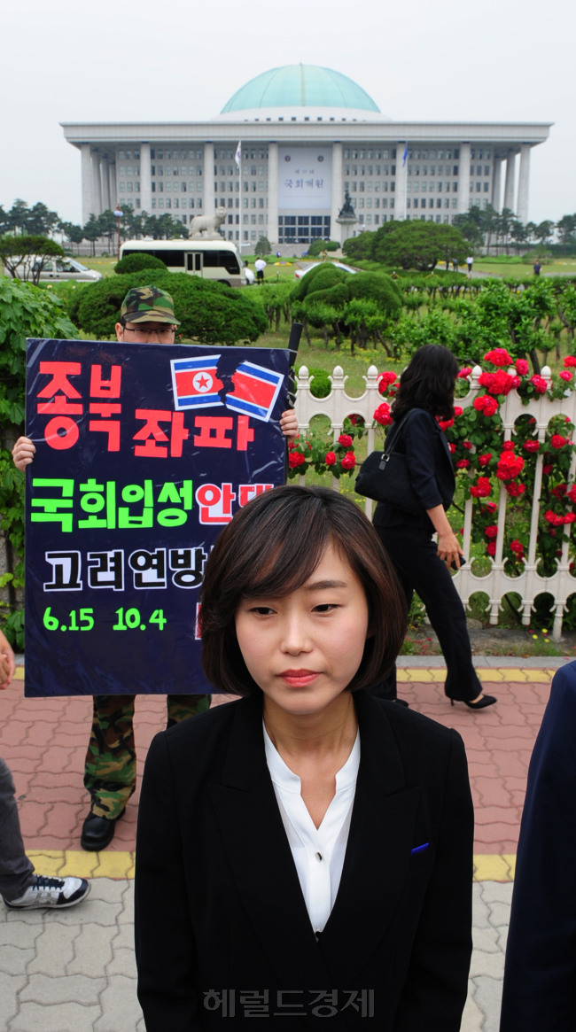 19대 국회가 개원한 30일 서울 여의도 국회의사당 앞에서 열린 반값등록금 촉구 집회에 참석한 김재연 통합진보당 의원 뒤로 한 1인 시위자가 종북좌파 국회입성 반대를 요구하는 피켓을 들고 서 있다. / 박현구 기자 phko@ 2012.05.30
김재연, 종북의원 국회 입성 반대 피켓, 국회의사당. 통합진보당 부정 경선과 관련해 자진 사퇴를 거부하고 있는 김재연ㆍ이석기 당선자 파문이 사진 한 장에 모두 담겨 있다. 김 당선자는 30일 서울 여의도 국회의사당 앞에서 열린 반값등록금 촉구집회에 모습을 드러냈다.  박현구 기자/phko@heraldm.com