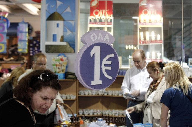 Customers browse discounted goods for sale at a “one euro store” in Athens.  Bloomberg