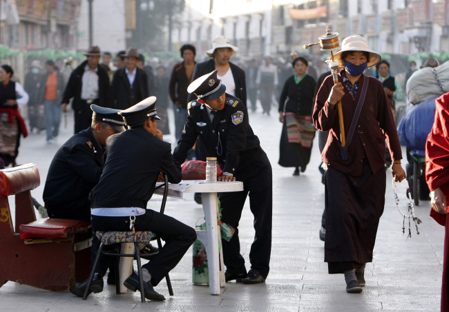 <YONHAP PHOTO-0806> FILE - In this June 19, 2009 file photo, security guards keep watch over Buddhist pilgrims as they walk on the Barkhor, the circular route around the Jokhang Temple in Lhasa, the capital of Tibet, China. Two men engulfed themselves in towering flames outside the temple that is a popular tourist site in Lhasa Sunday, MaY 27, 2012, marking the first time a recent wave of self-immolations to protest Chinese rule has reached the tightly guarded Tibetan capital. (AP Photo/Greg Baker, File)/2012-05-28 18:06:48/ <저작권자 ⓒ 1980-2012 ㈜연합뉴스. 무단 전재 재배포 금지.>
Security guards keep watch over Buddhist pilgrims as they walk on the Barkhor, the circular route around the Jokhang Temple in Lhasa, the capital of Tibet.  AP-Yonhap News
