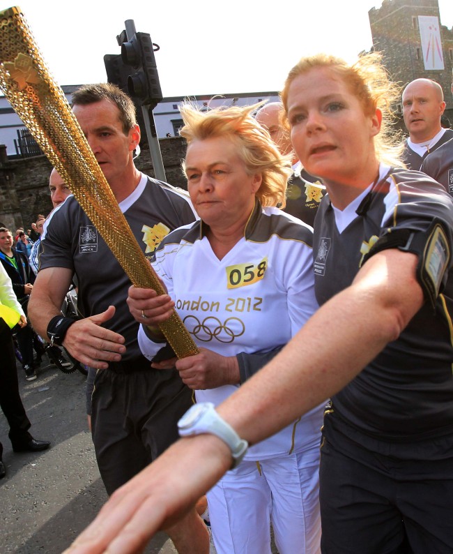 <YONHAP PHOTO-0263> The Olympic torch bearer is re-routed by Olympic securtiy personall after protestors tussle with police near Peace Bridge in Londonderry , Northern Ireland on June 4, 2012. The Olympic Torch relay started at Land's End, the southwest tip of England, to begin an 8,000-mile (12,875-kilometre) journey around Britain, with a detour to also visit the Irish capital Dublin. It will culminate in the flame being brought to the Olympic Stadium for the opening of the Games on July 27.AFP PHOTO / PETER MUHLY../2012-06-05 05:42:36/ <저작권자 ⓒ 1980-2012 ㈜연합뉴스. 무단 전재 재배포 금지.>
An Olympic torch-bearer is directed by Olympic security personnel in Londonderry, Northern Ireland, Monday.  AFP-Yonhap News