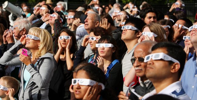 Hundreds of people gather wearing special viewing glasses gather to watch the transit of Venus at the University of Western Ontario in London on Tuesday.  AP-Yonhap News