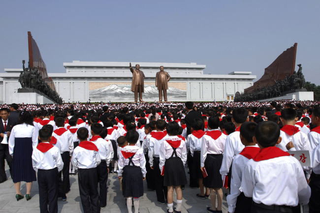North Korean students who were selected as delegates to the Korean Children’s Union, pay respects in front of bronze statues of late North Korean leaders Kim Il-sung and Kim Jong-il in Pyongyang, on Sunday.  (AP-Yonhap News)