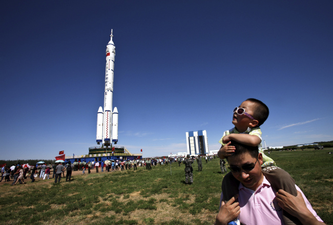 A man carries his son near the Long March-2F rocket carrying the Shenzhou-9 spacecraft on the launch pad of the Jiuquan launch center in Jiuquan, Saturday.  (AP-Yonhap News)
