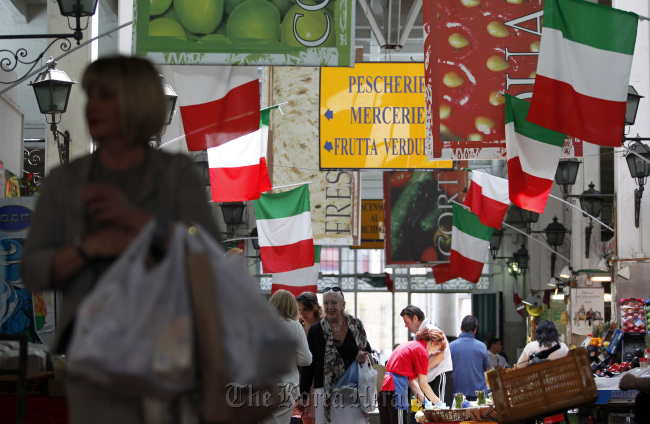National flags of Italy hang above stalls at an indoor market in Rome.  (Bloomberg)