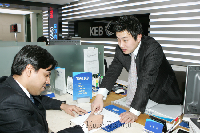 A bank clerk at Korea Exchange Bank’s Global Desk attends to a foreign customer in Seoul.  KEB