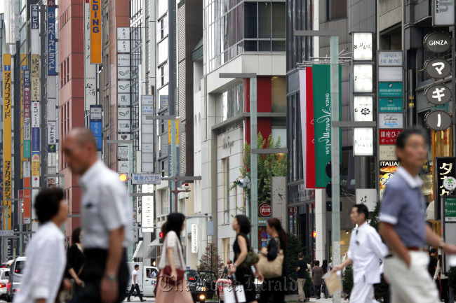 Pedestrians walk past commercial buildings in the Ginza district of Tokyo.  Bloomberg