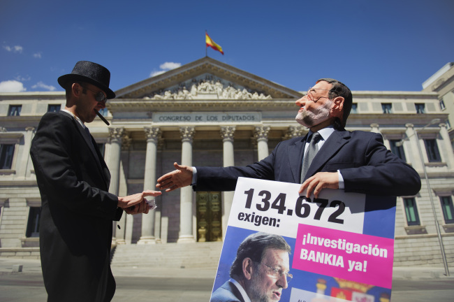 Actors representing the roles of Spanish Prime Minister Mariano Rajoy (right) and a banker pose while staging a flash mob protest against Bankia, outside the Spanish Parliament in Madrid on Tuesday.  AP-Yonhap News