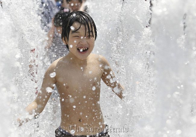 Children enjoy running through a large fountain in downtown Seoul.  Yonhap News