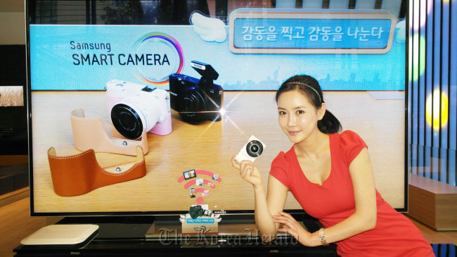 A model holds up Samsung Electronics’ new mirrorless camera named “NX1000,” which supports Wi-Fi for easy storing, editing and sharing of photos, at the company’s office in southern Seoul on Thursday.   (Samsung Electronics)