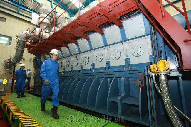 Hyundai Heavy Industries workers test-run “HiMSEN H35/40GV,” an independently developed environment-friendly gas engine, at its Ulsan headquarters on Friday. Invented in 2010 and scheduled to be exported for the first time this month to the Middle East, HiMSEN boasts low emissions and high power-efficiency. The engine can be used to generate power for offshore plants like drill ships. (HHI)