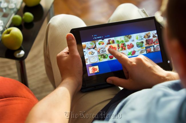 A man browses grocery shopping websites with tablet PC