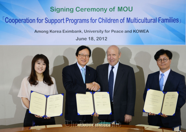 Korea Eximbank chairman and CEO Kim Yong-hwan (second from left) and University for Peace rector John J. Maresca (third from left) shake hands after signing an MOU to cooperate for support programs for children of multicultural families on Monday in Seoul.    (Korea Eximbank)