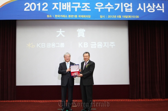 KB Financial Group chairman Euh Yoon-dae (right) poses with Financial Servicies Commission chairman Kim Seok-dong after the lender was named the company with the best corporate governance structure in Korea by the Corporate Governance Service on Tuesday in Seoul. KB Financial