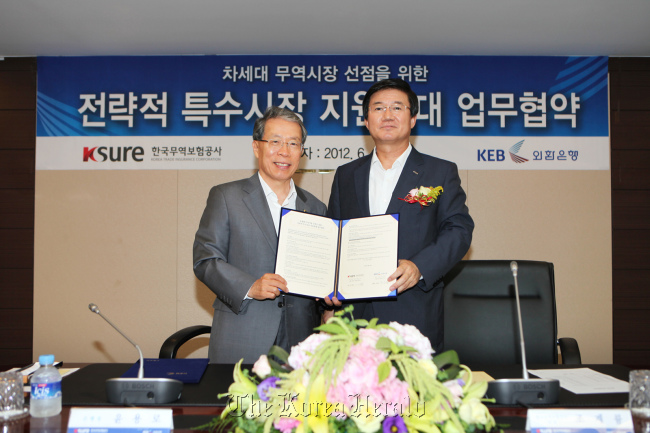 Korea Exchange Bank CEO Yun Yong-ro (left) poses with Cho Kye-ryoong, CEO of the Korea Trade Insurance Corp. or K-Sure, after signing an MOU to increase support for strategically important markets at the lender’s headquarters in Seoul on Tuesday.  (KEB)