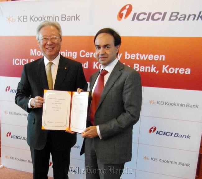 KB Kookmin Bank vice president Lee Chan-keun (left) and Vijay Chandok, ICICI Bank president for international banking and small and medium enterprises pose on Tuesday at a signing ceremony in Mumbai, India.   KB Kookmin Bank