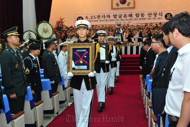 Members of the honor guard carry the medal awarded to those who died during the Korea War and their remains at the National Cemetery in Daejeon on Wednesday. The military buried the remains of 10 soldiers who have been identified in a burial ceremony on Wednesday.  (Army)
