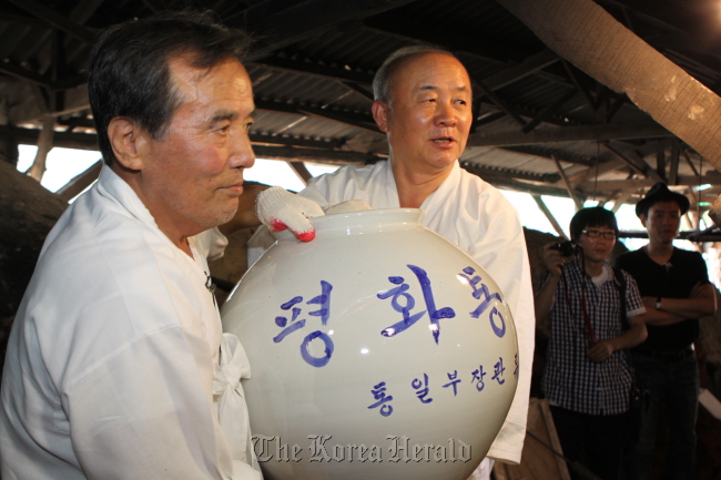 Minister of Unification Yu Woo-ik (right) and potter Kim Jeong-ok carry one of the six unification jars in Mungyeong, North Gyeongsang Province on Saturday.  Ministry of Unification