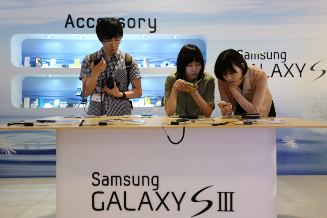 Members of the media try out the Samsung Electronics’ Galaxy S3 smartphone at a launch event in Seoul on Monday.  (Bloomberg)