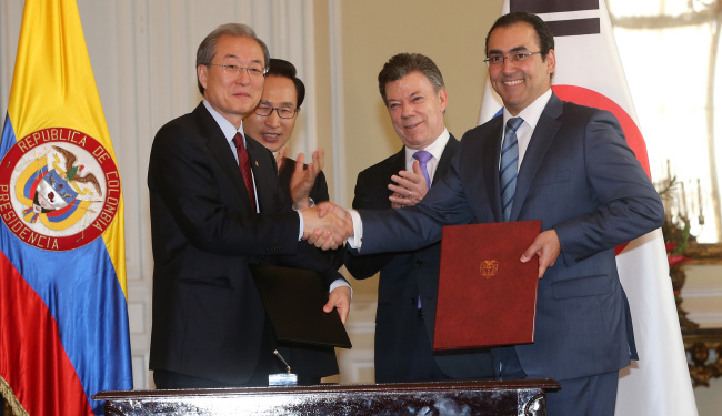 Korean Trade Minister Bark Tae-ho (left) and his Colombian counterpart Sergio Diaz-Granados shake hands after signing a joint statement declaring the end of negotiations in a ceremony in Bogota on Monday attended by Korean President Lee Myung-bak and Colombian President Juan Manuel Santos.    (Yonhap News)